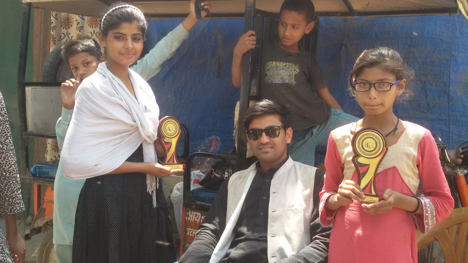 Students celebrating an achievement with trophies alongside ARP India volunteers